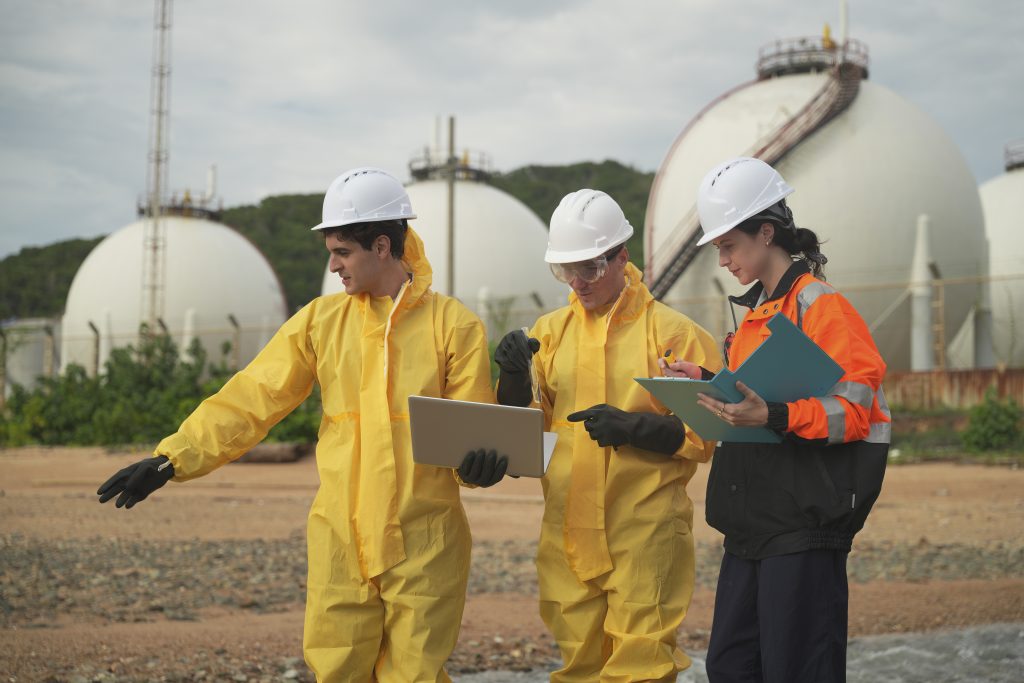 Trabajadores con equipo de protección discuten los procedimientos de seguridad en una instalación industrial durante el día - Antioqueña de Transportes